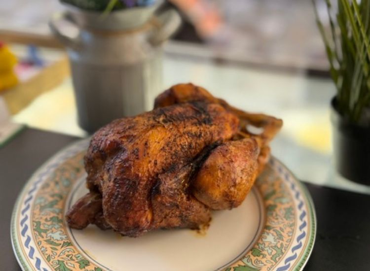 Poulet rôti doré et croustillant servi sur une assiette décorée, accompagné d'une cruche en arrière-plan
